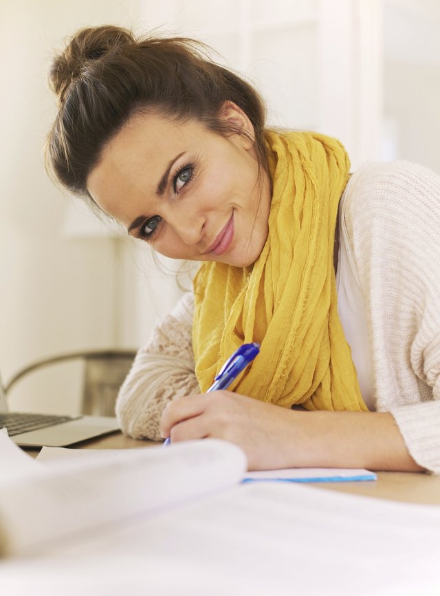 A woman writes in a notebook.