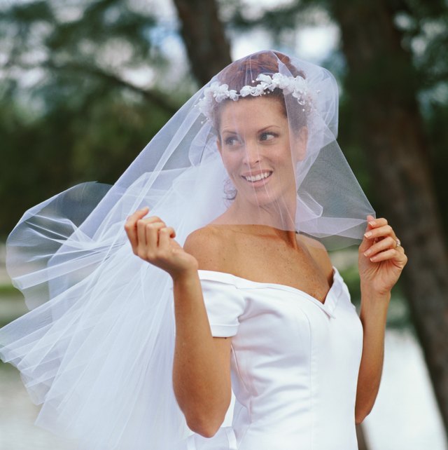 Part of the veil is draped over the bride's face during the wedding ceremony.