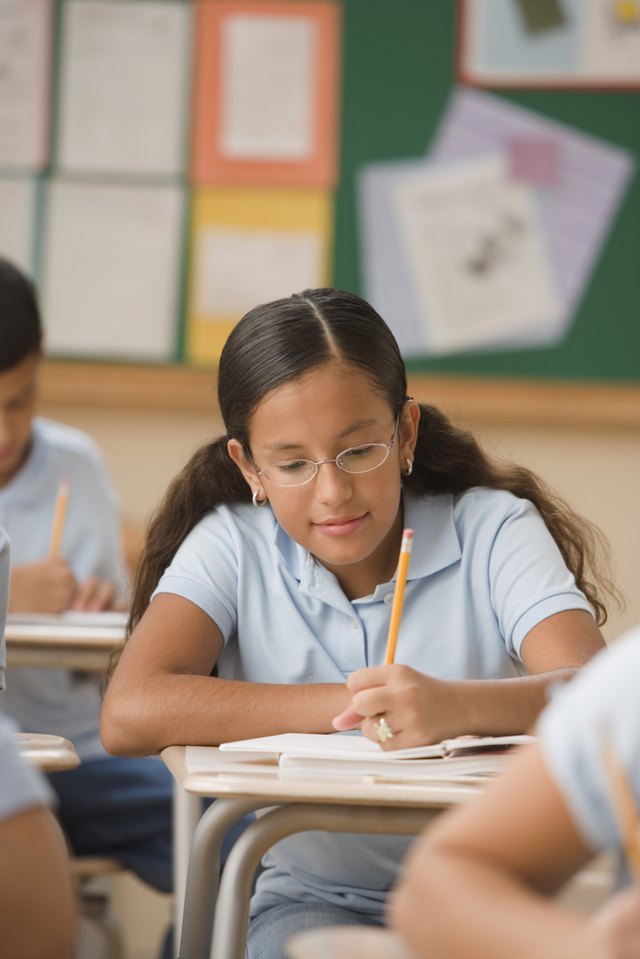 A female students writes on a notepad in a classroom.