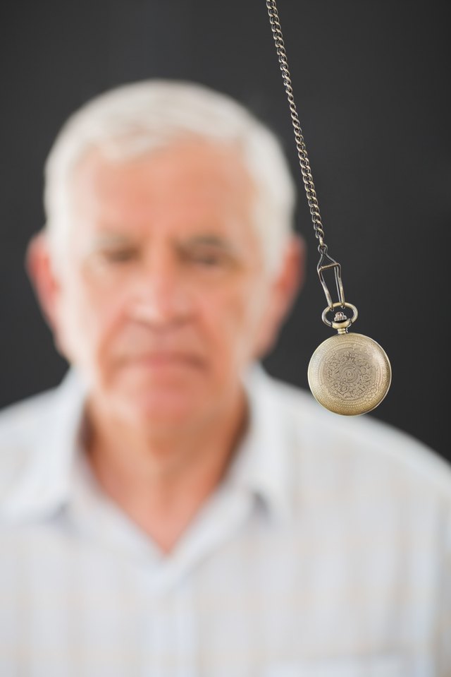 Elderly man watching swinging pendulum
