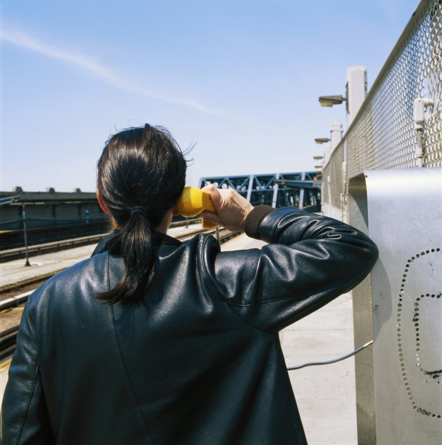 Man wearing leather jacket and using payphone.