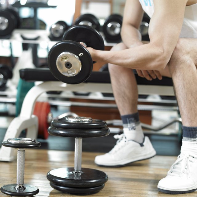 A man is doing bicep curls at the health club.