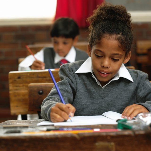 Students writing at desks in classroom. Students writing at desks in classroom.