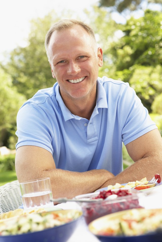 A man sits at an outdoor table at a potluck.