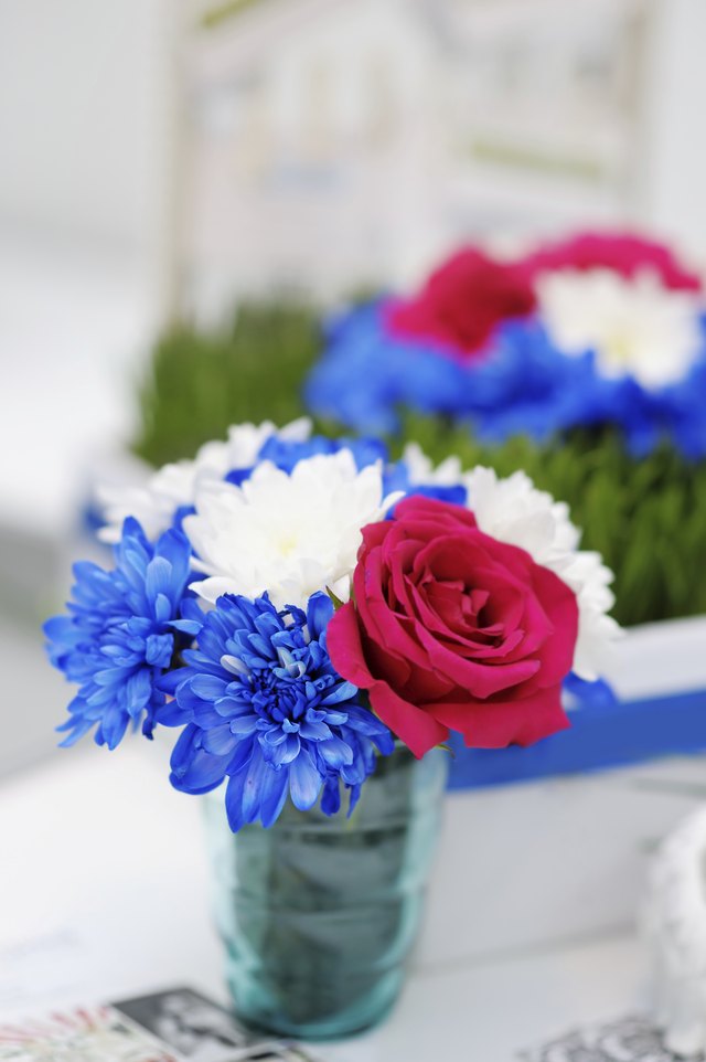 Small vase filled with red, white, and blue flowers. Small vase filled with red, white, and blue flowers.
