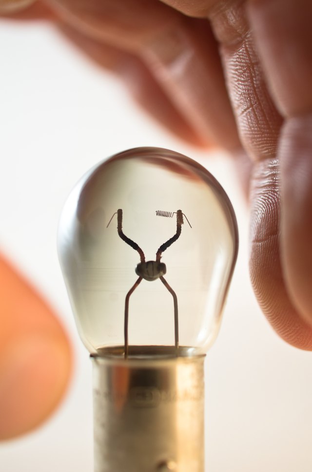 Hand reaching for burned out light bulb