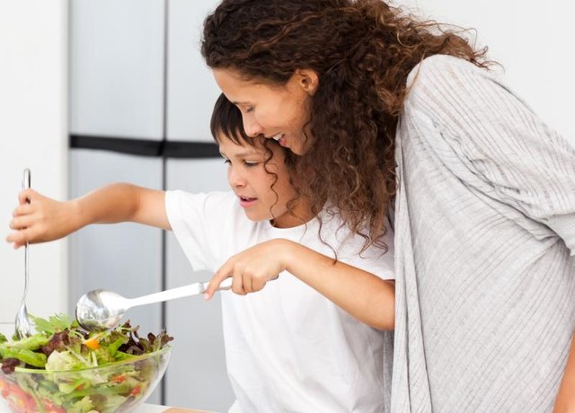 Child helping mother prepare a salad. Child helping mother prepare a salad.