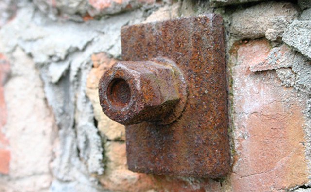 Nuts and bolts support a brick wall.