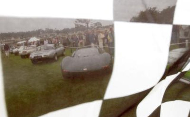 Row of vintage Jaguars seen through checked flag at Pebble Beach, CA.