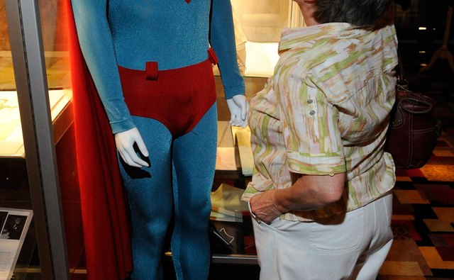 A woman looks at a Superman costume on a mannequin.