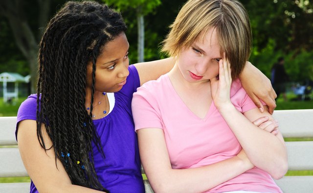A girl puts her arm around a friend who is upset.