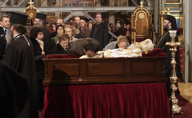 Mourners view the deceased in an open casket.