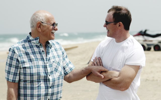 A father and son have a conversation on a beach.