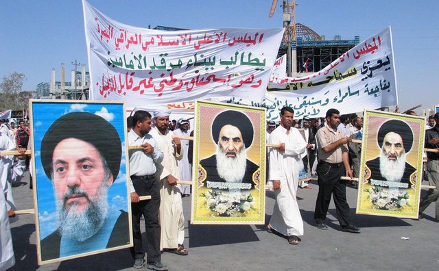 Shiite Muslims carry pictures of one of their major religious leaders, Grand Ayatollah Ali al-Sistani, during a protest.