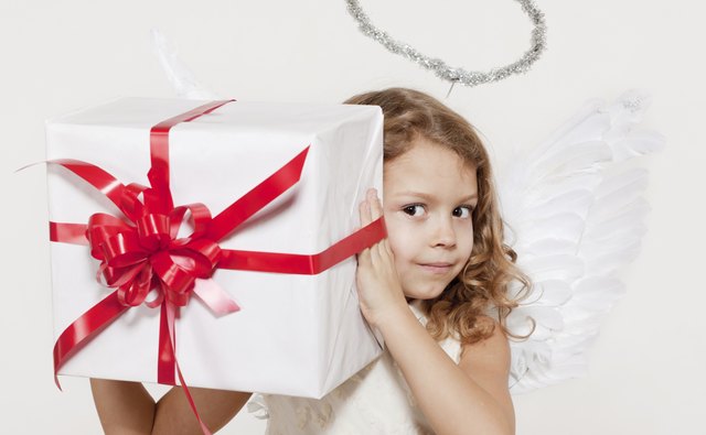Little girl dressed as an angel and holding a present.