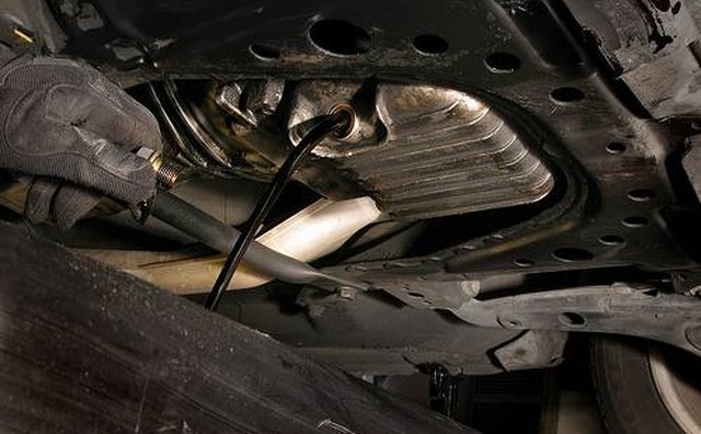 The drain plug is at the bottom of the oil pan.