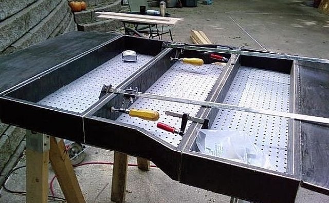 Securing three smaller boxes together with bolts.