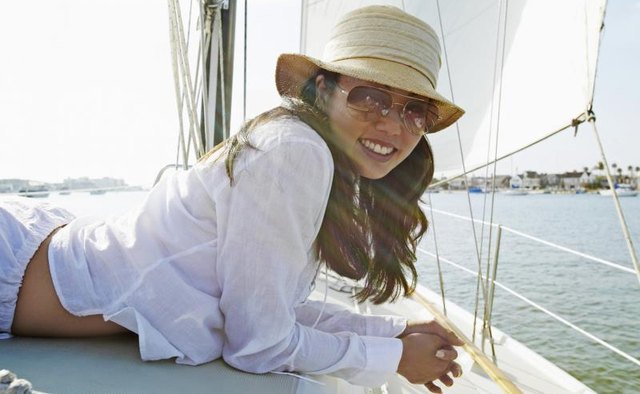 A straw hat protecting a woman on a boat deck from the sun.