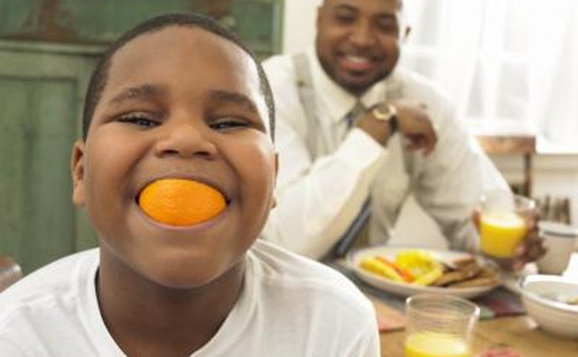 Boy with an orange in his mouth.