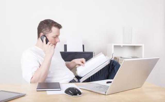 Young man working on an office, talking on the phone.