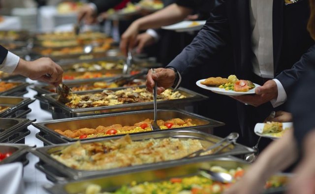 People gather around the buffet to help themselves to food