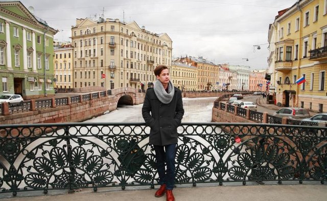 A young Russian man standing on a bridge.