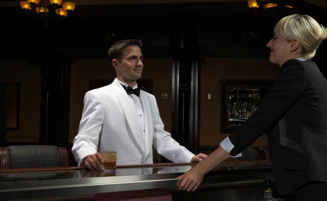 A bartender wears a white tuxedo jacket.