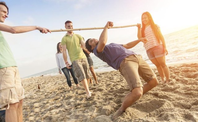 Friends dancing the limbo on the beach.