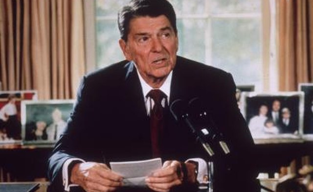 President Ronald Reagan sitting at his desk in the Oval Office, circa 1985
