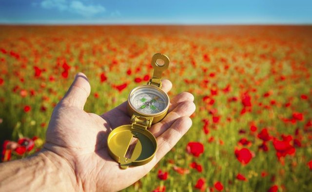 Man's hand holding a modern compass.