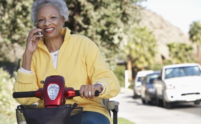 Senior woman using scooter on sidewalk