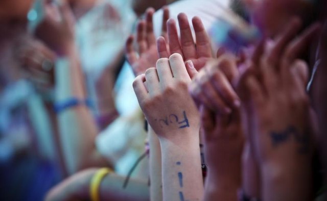 A close-up of an audience clapping to live music.