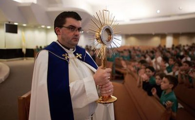 Rev. carries a monstrance during a mass in Boca Raton, FL.