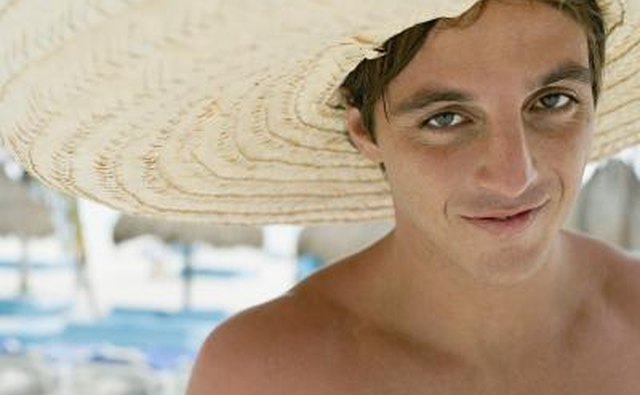 Young man wears straw sombrero at beach