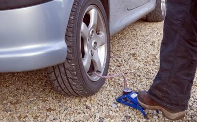Woman pumping up tire of car