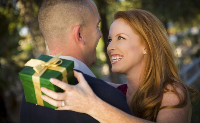 A military man and a smiling woman are exchanging gifts.