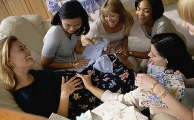 Women touching woman's stomach at baby shower.