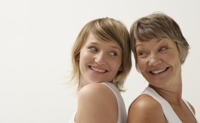Mother and daughter smiling and standing back to back.
