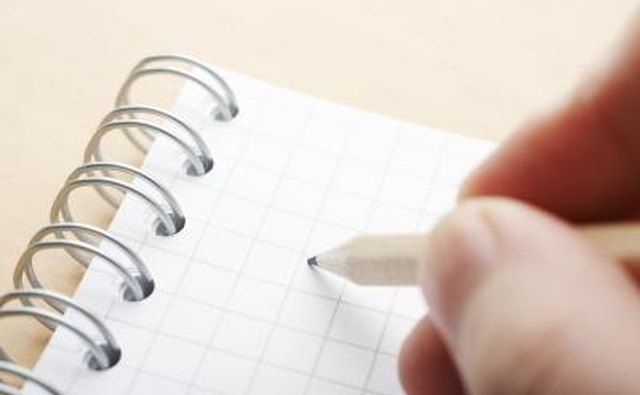 Person writing with pencil in a notebook.