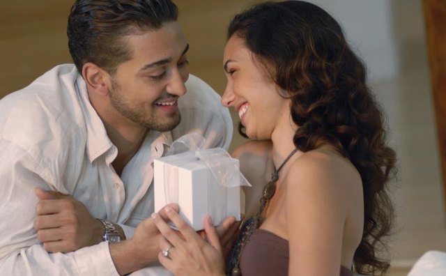 Man handing his wife a small wrapped gift