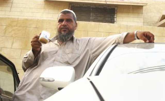 Muslim man standing outside drinking coffee