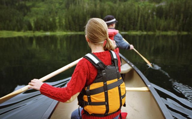 Father and daughter rowing in canoe on lake