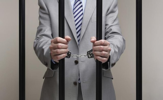 A man dressed in a business suit behind bars.