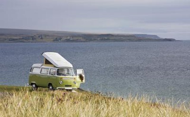 VW bus parked in a field overlooking water.