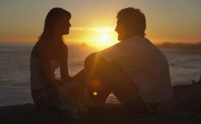 Couple talking near coast at sunset