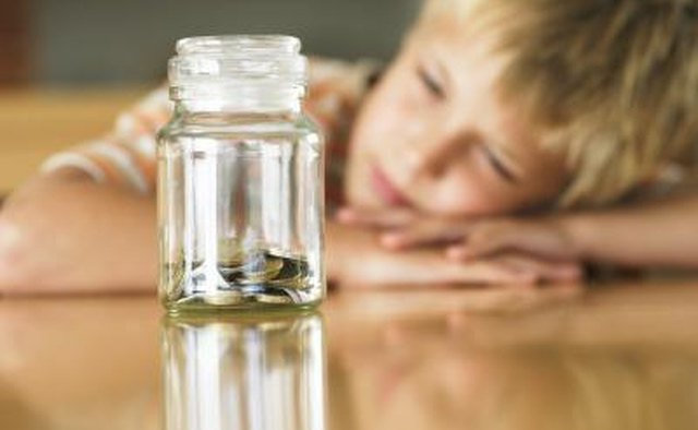 Young boy looking at jar of coins.