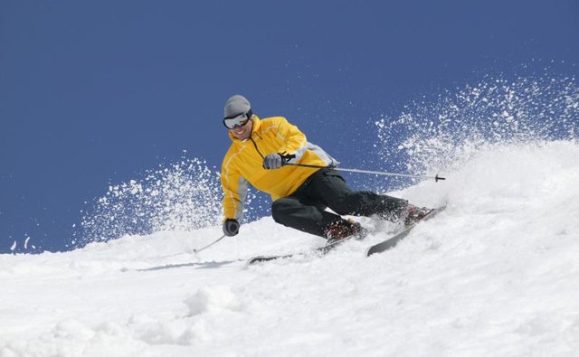 Man downhill skiing in snow.