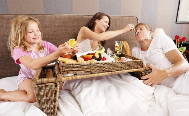 A family having breakfast together in bed.