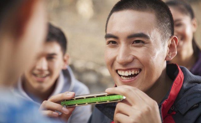 Smiling young man holds a harmonica.