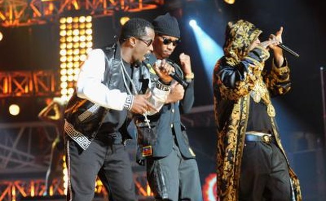 Three hip hop artists perform on stage.